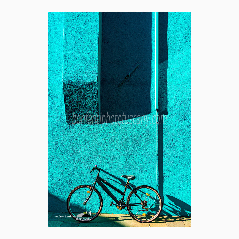 una bici su muro turchese in luce radente.jpg