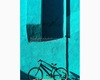 una bici su muro turchese in luce radente.jpg